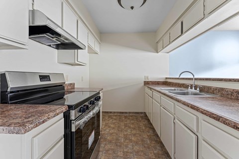 A kitchen with a black stove top oven and a granite counter top.