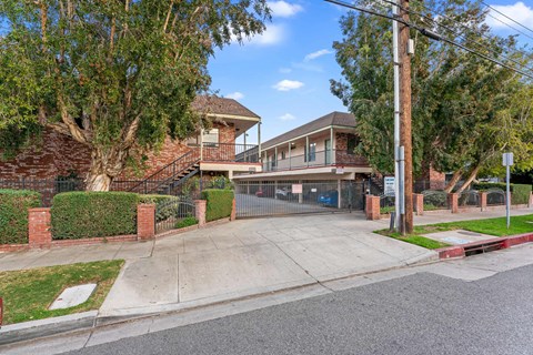 A residential street with a house and a tree in front.