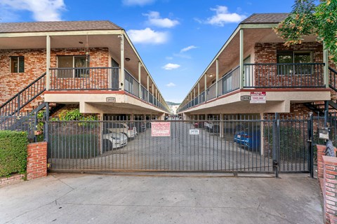 A gated entrance to a brick apartment complex.