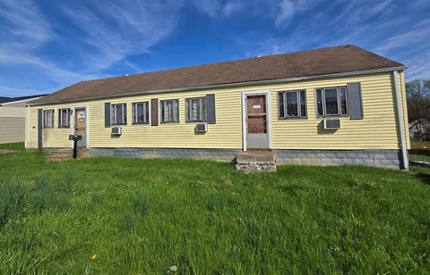 A yellow house with a brown roof and a brown door.