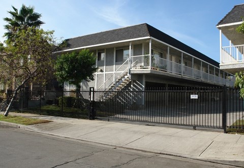 A black house with a white fence and a tree in front.