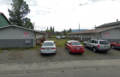 Three cars are parked in a lot with a sign on the wall.