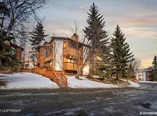 A house with a snow-covered front yard and evergreen trees.