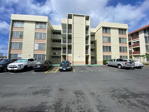 A parking lot with cars and apartment buildings in the background.