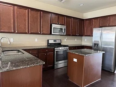 A kitchen with brown cabinets and a granite countertop.