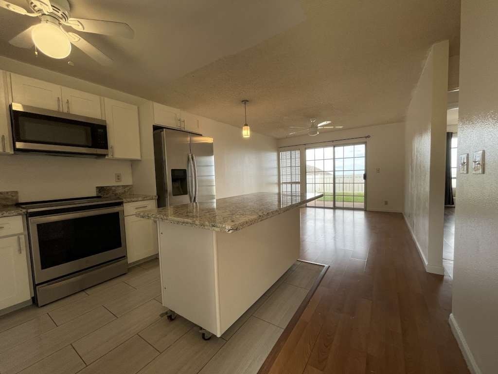 A kitchen with white cabinets and a marble island.