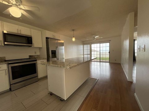 A kitchen with white cabinets and a marble island.