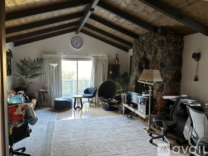 A room with a ceiling fan, a chair, a desk, and a couch.