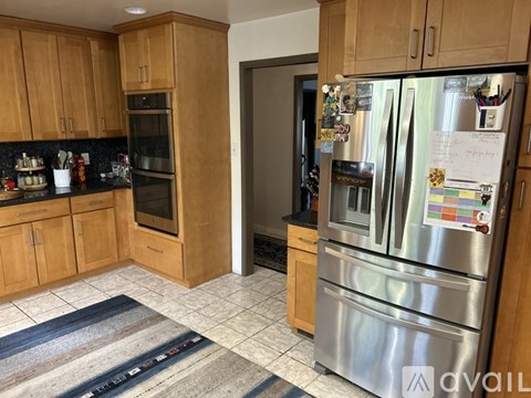 A kitchen with wooden cabinets and a stainless steel refrigerator.