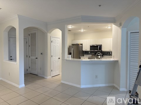 A kitchen with white cabinets and a countertop with a sink and microwave.