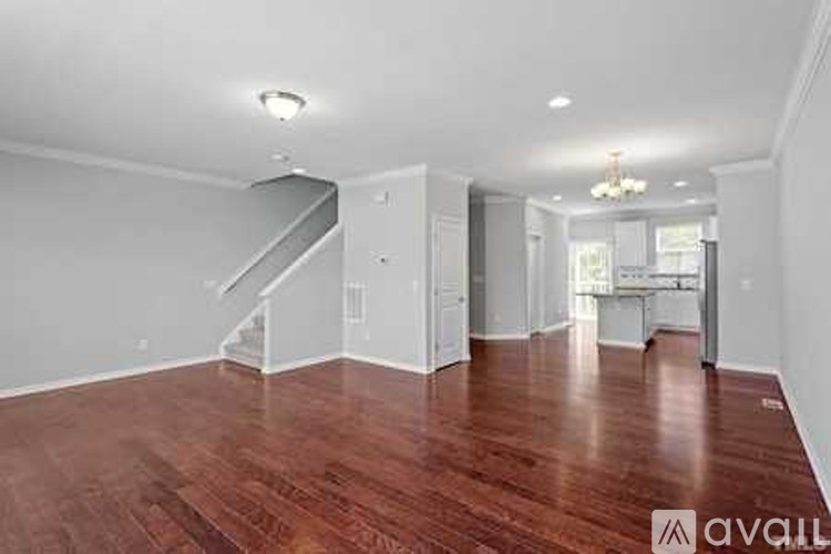 A spacious room with wooden floors and a staircase.