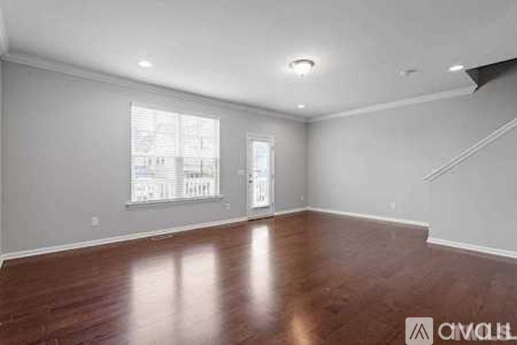 A spacious room with wooden floors and white walls.
