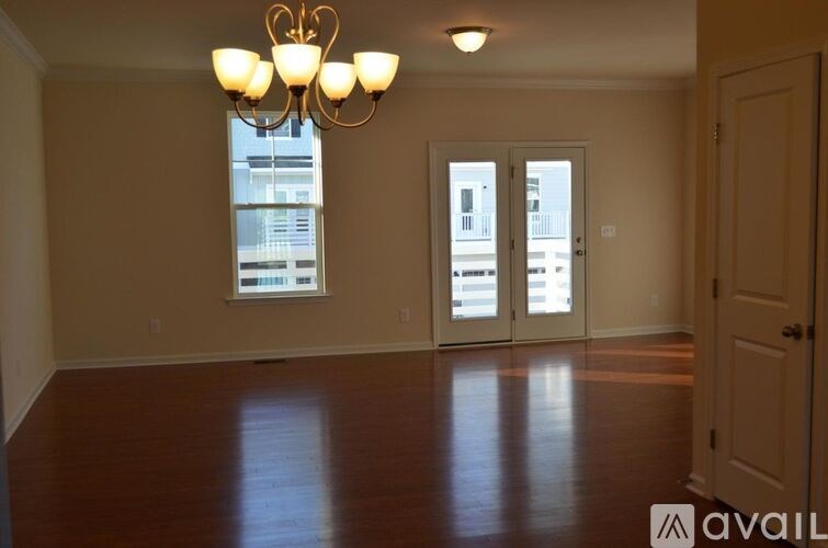 A room with a chandelier, two doors, and a window with a view of a balcony.