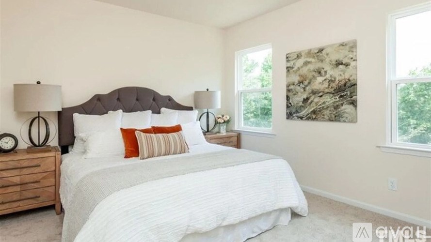 A bedroom with a large bed and two lamps on either side of the bed.