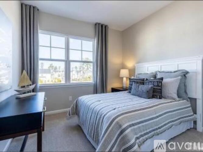 A bedroom with a large bed and a window overlooking a tree-filled landscape.