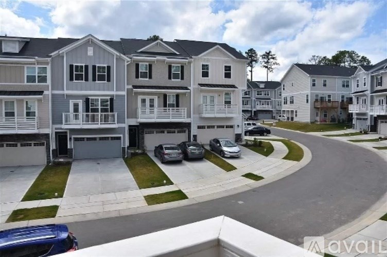 A row of townhouses with a car parked in front of the first one.