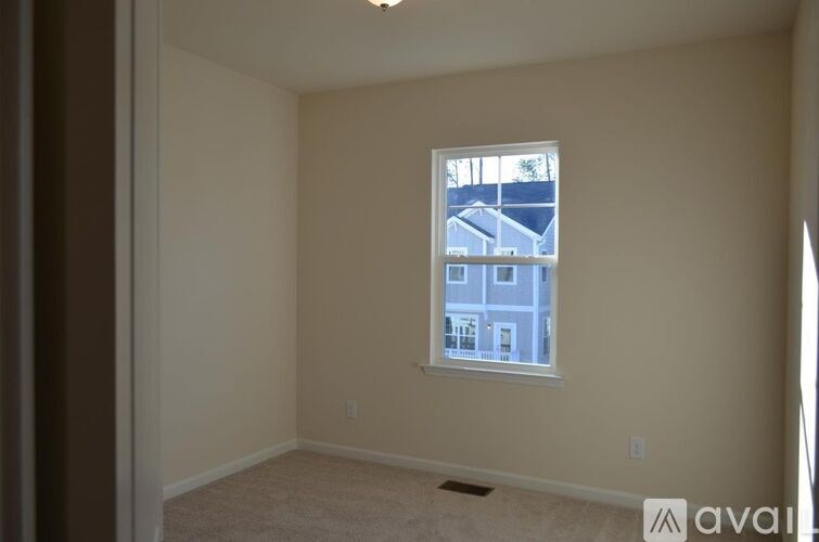 A room with a window showing a view of a house across the street.