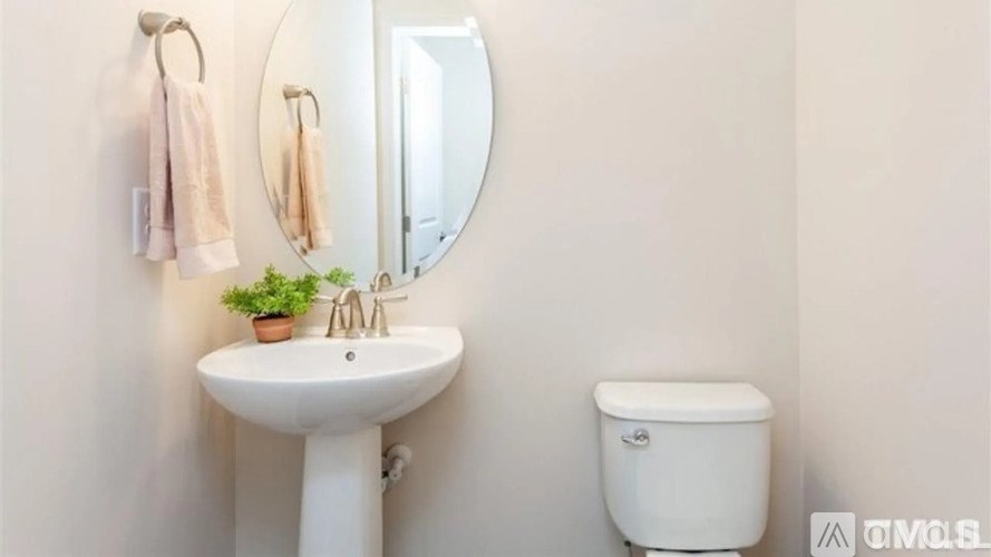 A white sink and toilet in a bathroom with a mirror and towel rack.