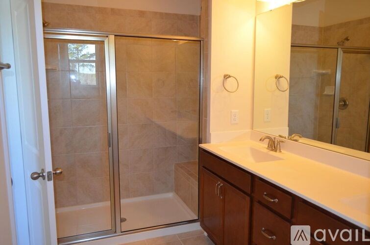 A bathroom with a sink, mirror, and shower.