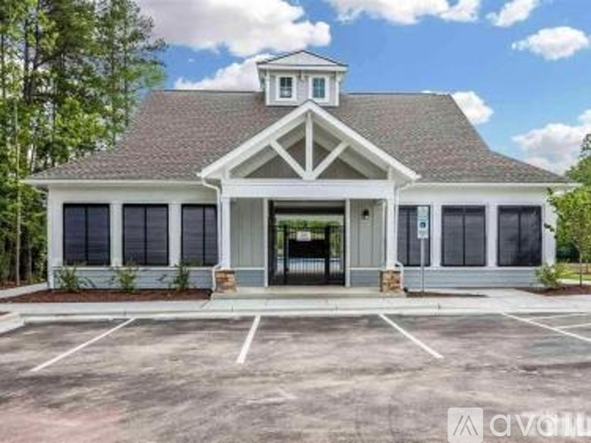A white building with a black roof and a parking lot in front.