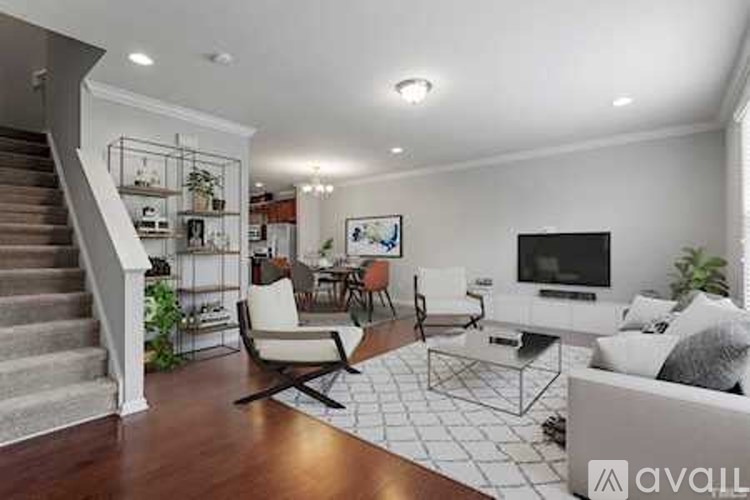 A living room with a staircase on the left side and a television on the right side.
