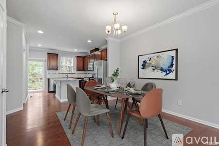A dining room with a table set for four and a painting on the wall.