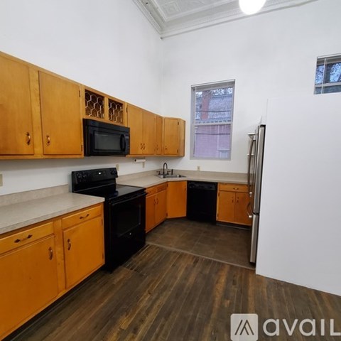 A kitchen with wooden cabinets and black appliances.