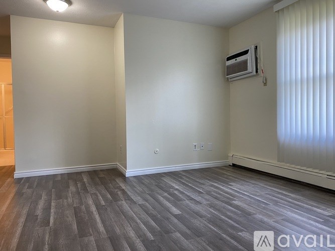 A room with a grey floor and a window with blinds.