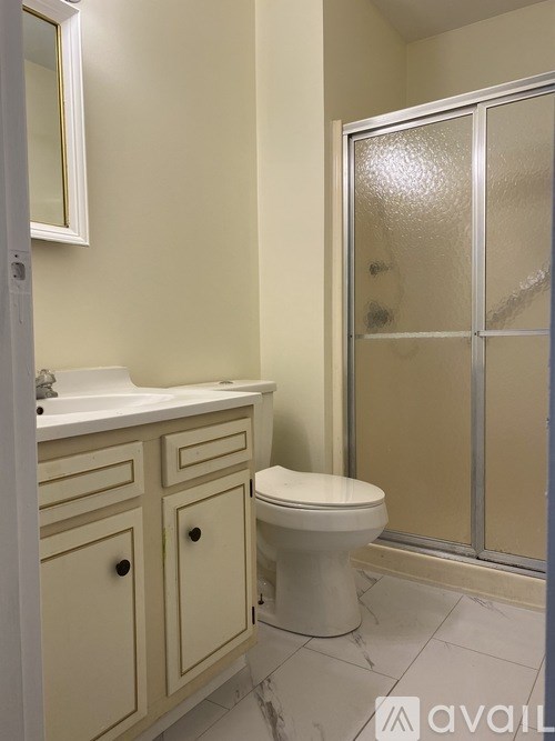 A white toilet sits in a bathroom next to a sink and a shower.