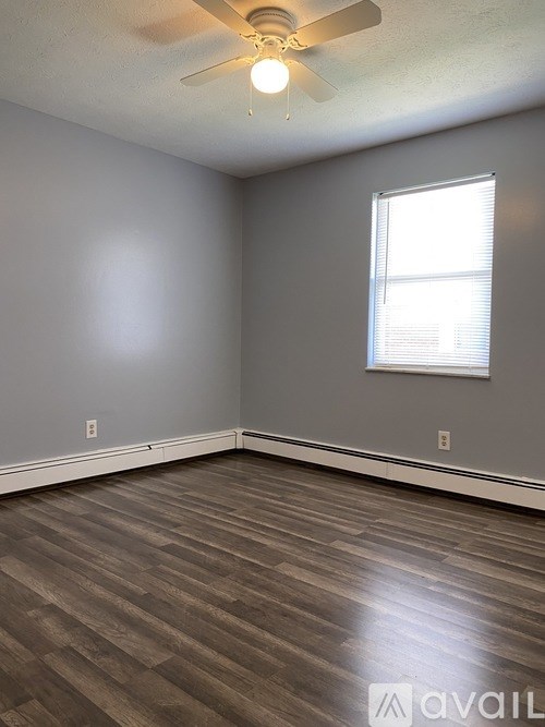 A room with a ceiling fan and a window with blinds.