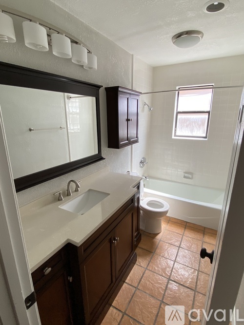 A bathroom with brown cabinets and a white sink.