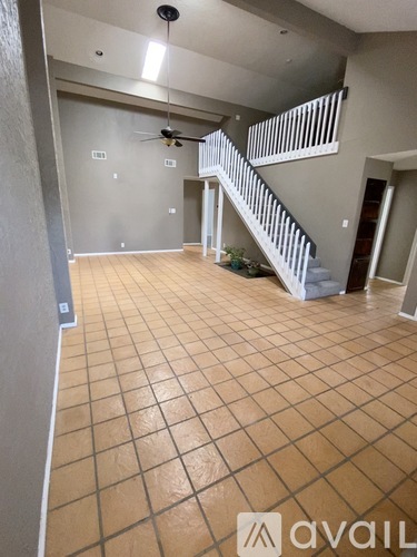 A spacious room with a staircase and a ceiling fan.