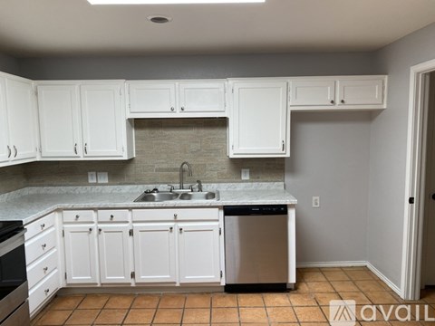 A kitchen with white cabinets and a stone backsplash.