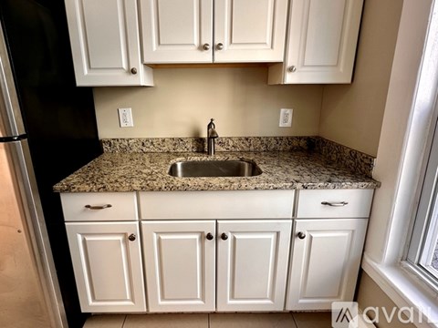 A kitchen with white cabinets and a granite countertop.