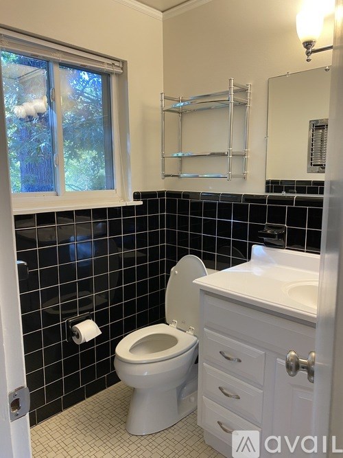 A white toilet and sink in a bathroom with black tiles.