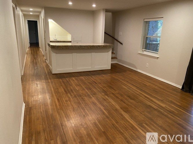 A spacious room with wooden flooring and a counter in the middle.