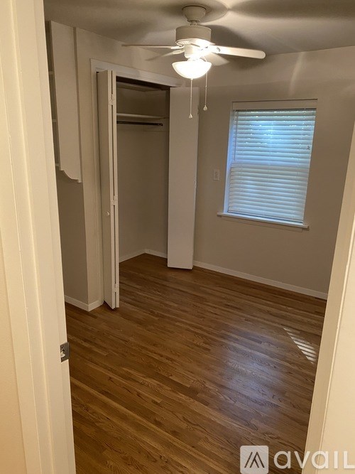 A room with a ceiling fan and wooden flooring.