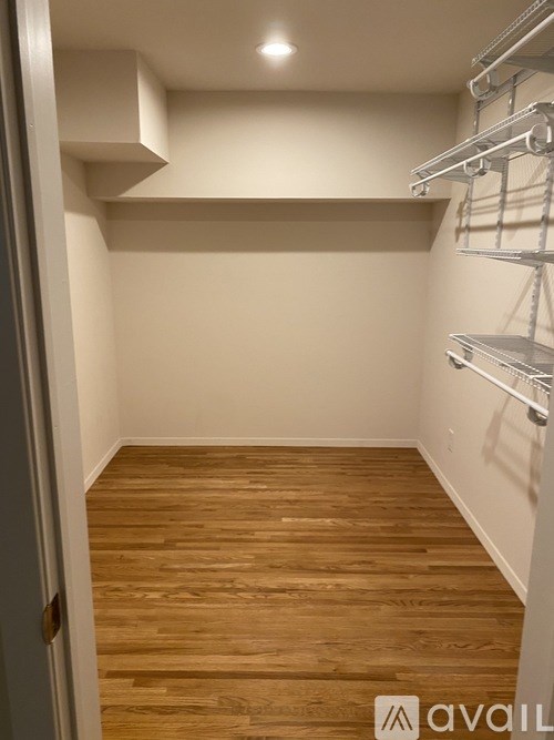 A room with wooden floors and white walls with shelves on the wall.