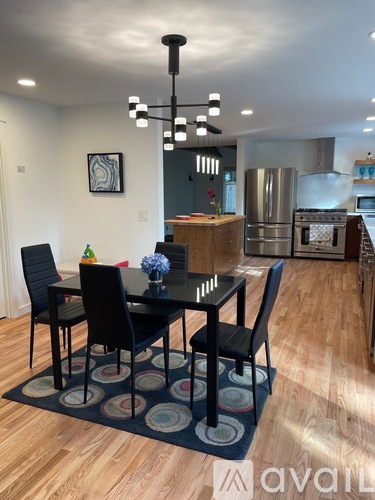 A dining room with a black table and chairs.