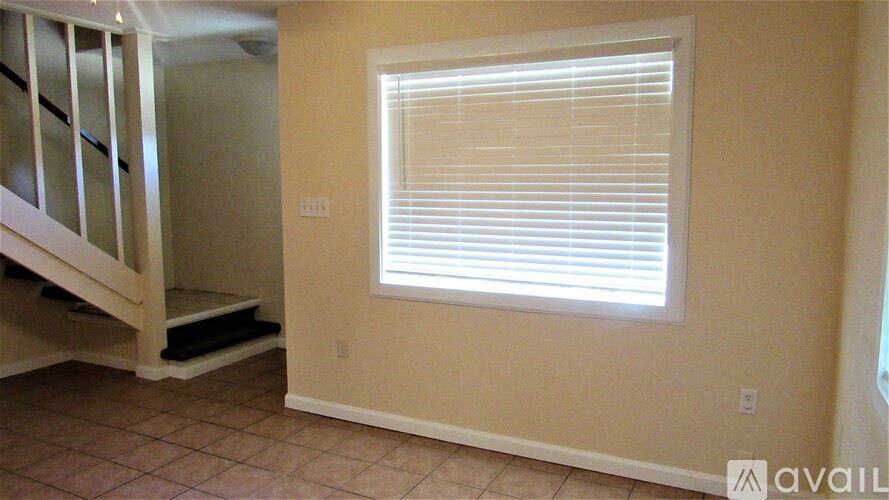 A room with a window covered by white blinds.