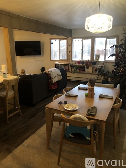 A living room with a couch, a television, a dining table with chairs, and a Christmas tree.