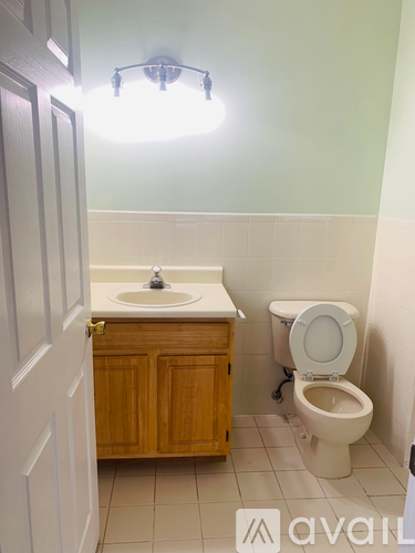 A bathroom with a toilet, sink, and cabinet.