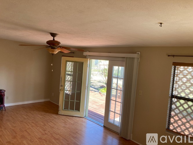A room with a ceiling fan and sliding glass doors.