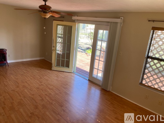 A room with a ceiling fan and sliding glass doors.