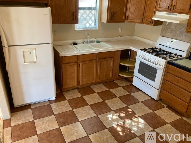 A kitchen with a white fridge, white stove, and brown cabinets.