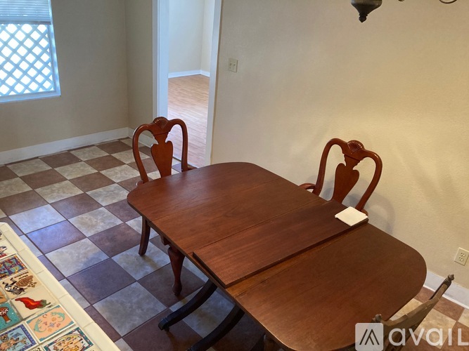 A wooden table with two chairs and a checkered floor.