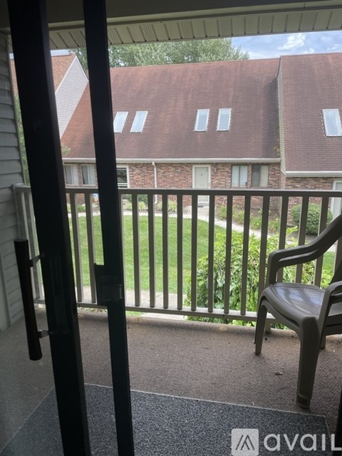A balcony with a chair and a view of a red brick building.