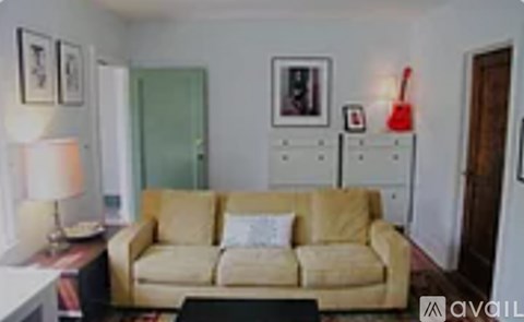 A living room with a tan couch and a red guitar on the wall.