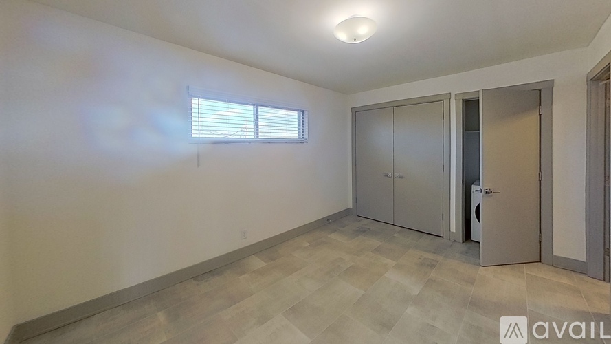 A room with a wooden floor, a window with blinds, and a wall with a logo that says "AVAIL".