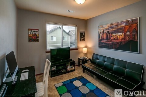 A living room with a green couch and a painting on the wall.
